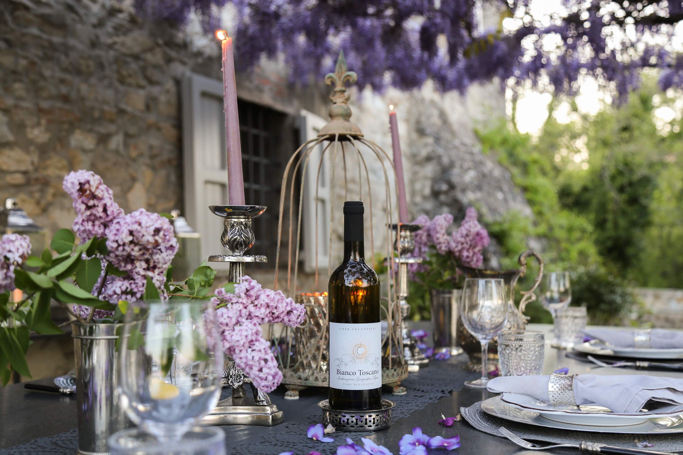 Evening table set with wine beneath wisteria at Tenuta Ceccatelli